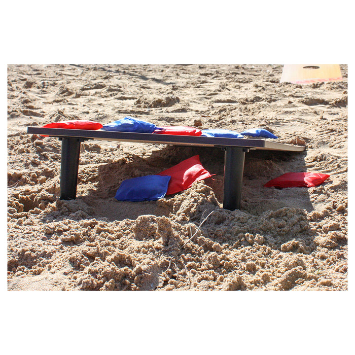 Board on stilts on sand, with red and blue bean bags on top