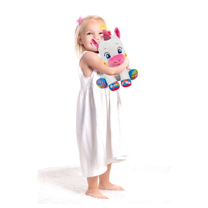 Young girl stood up holding unicorn toy 